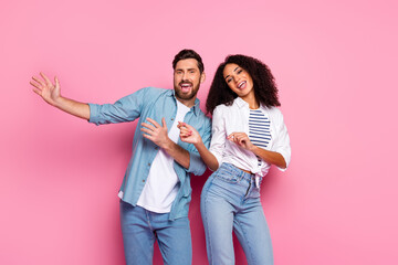 Young smiling couple in colorful casual clothing celebrating fun together on a pink vibrant...