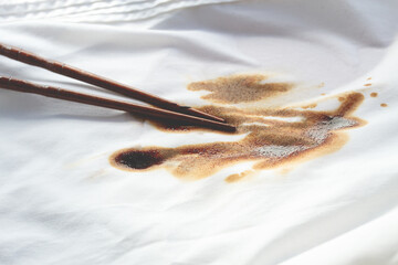 White shirt stained with soy sauce and chopsticks lying on it, no people, close-up , selective focus,