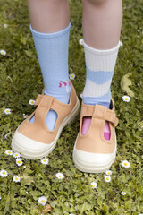 Kid wears different pair of socks. Child foots in mismatched socks, studio photography. Down syndrome awareness concept, odd socks day, anti-bullying week.	