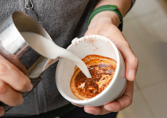 A barista prepares a latte at a professional espresso machine in a cozy coffee shop. The scene captures the meticulous process of brewing coffee, with various barista tools.