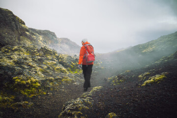 A male hiker at Leirhnjúkur Volcano's colorful geothermal area with lava fields, sulfur deposits,...