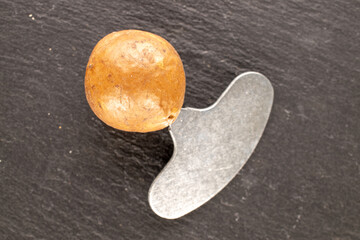 Macadamia nuts in shell with metal key on slate stone, top view.