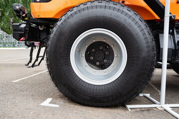 Close-up of a tractor wheel with orange rim on grassy ground.