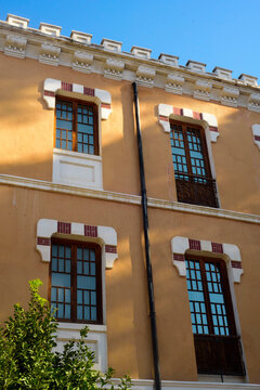 Ventanas con marco de moludura y ladrillo en fachada amarilla de Cuartel de Artiller&iacute;a de Murcia