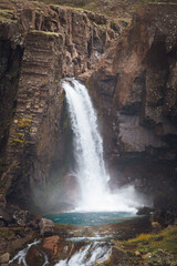 Scenic Icelandic waterfall cascading over basalt cliffs, surrounded by mossy terrain