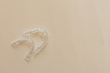 close up top view dental aligner retainer (invisible) on beige color background at dental clinic...