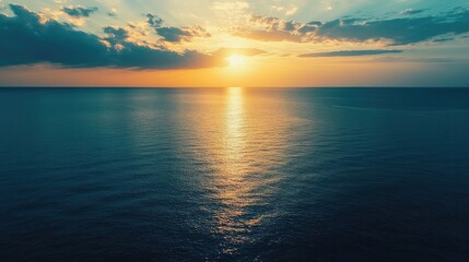 Obraz premium Aerial view of tranquil ocean water reflecting sunset colors with soft clouds and ample space for adding text or graphics