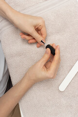A close-up view of hands applying clear nail polish during a manicure process.  self-care. beauty tutorials or nail care promotion.