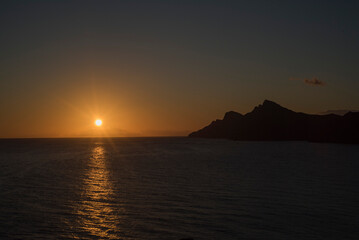 Sol poni&eacute;ndose en mar mediterr&aacute;neo y litoral rocoso