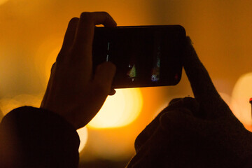 A smartphone held by a person, skillfully capturing a vibrant night scene filled with blurred, colorful lights and artistic reflections