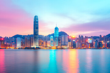 Obraz premium Vibrant urban cityscape at dusk with colorful lights reflecting on water