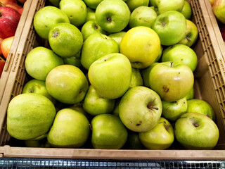 Fresh green apples gathered in a wooden crate at a local market during the daytime