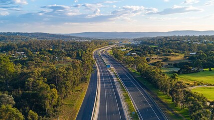 A modern motorway stretching into the horizon, surrounded by lush green landscapes and a bright blue sky.