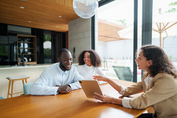 Professional real estate agent in business attire presents property details using tablet to diverse...