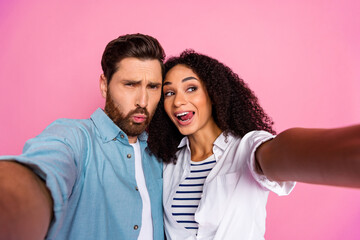 Young couple taking a selfie on a pink background showcasing joy and togetherness