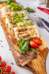 Lavash with chicken, baked on grill, served on wooden board