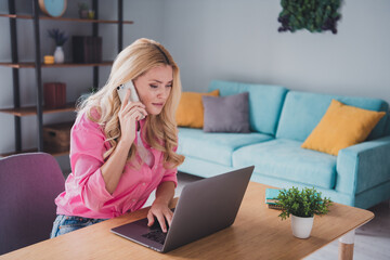 Young woman multitasking with laptop and phone in cozy living room during daylight