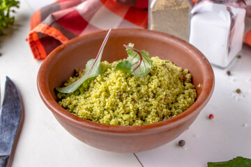 Couscous in bowl with olive oil and dried tomatoes on white background
