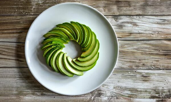 Sliced avocado art arranged in circle on white plate