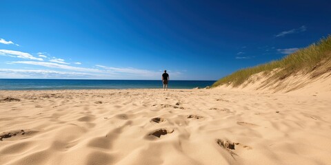 A solitary figure walking along a tranquil beach shore, embodying feelings of introspection, serenity, and the calming influence of the ocean under a clear blue sky.