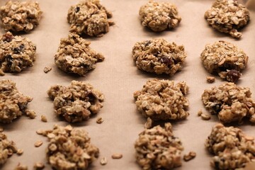 The process of preparing homemade oatmeal cookies - raw, formed cookies placed on a baking tray lined with baking paper