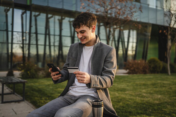 Obraz premium adult man use mobile phone and credit card for online shopping outdoor