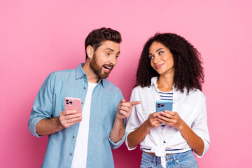 Happy couple using smartphones together on pink background for lifestyle or technology advertising