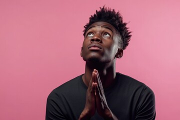 Obraz premium Young man prays with hope, conveying deep emotions against pink