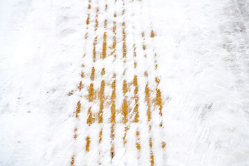 Yellow tactile paving covered in snow and ice close-up. Difficult conditions for movement visually impaired and blind pedestrians navigating icy and snowy sidewalks during winter.