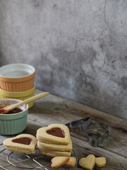 Heart shaped cookies decorated with strawberry jam along with kitchen utensils