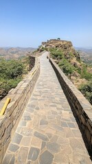 Fototapeta premium A peaceful hilltop view features a fence with a stunning mountain backdrop in India under a clear blue sky