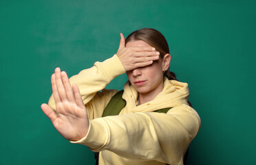covering face with hand and putting other hand up front to stop camera, refusing photos or pictures