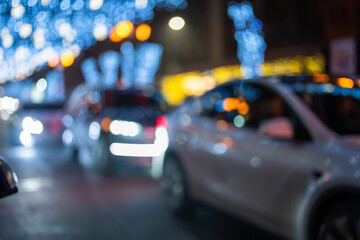 Fototapeta premium Christmas lights bokeh on the street, cars passing by on the road