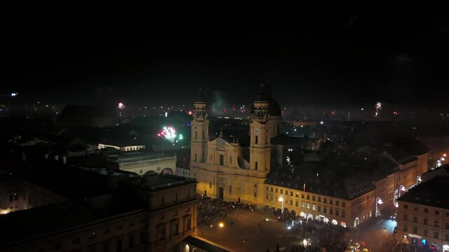 Aerial shot at midnight of fireworks and firecrackers lighting up downtown Munich, Germany, Odeonplatz. Feldherrnhalle and Theatinerkirche stand as part of festive scene. Silvester Feuerwerk Muenchen