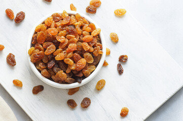 Dried grapes in wooden bowl or scoop on rustic background, healthy dry fruit concept, raisins