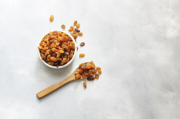 Dried grapes in wooden bowl or scoop on rustic background, healthy dry fruit concept, raisins