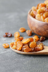 Dried grapes in wooden bowl or scoop on rustic background, healthy dry fruit concept, raisins