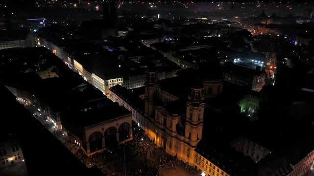 Aerial shot at midnight of fireworks and firecrackers lighting up downtown Munich, Germany, Odeonplatz. Feldherrnhalle and Theatinerkirche stand as part of festive scene. Silvester Feuerwerk Muenchen