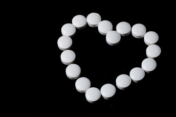 White round tablets are scattered on a black background.