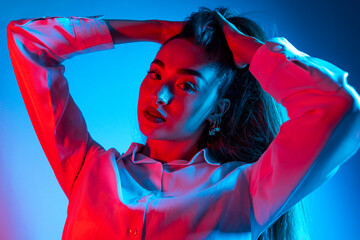 High Fashion model woman in colorful bright neon blue and purple lights posing in studio. Portrait...