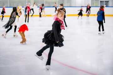 Little girl in reindeer costume skating on ice rink, children's sports festival.