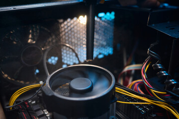 A man cleans a computer case with a vacuum in a bright room, stressing workspace tidiness
