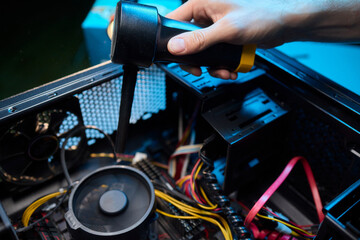 A man cleans a computer case with a vacuum in a bright room, stressing workspace tidiness