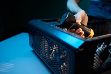 A man cleans a computer case with a vacuum in a bright room, stressing workspace tidiness