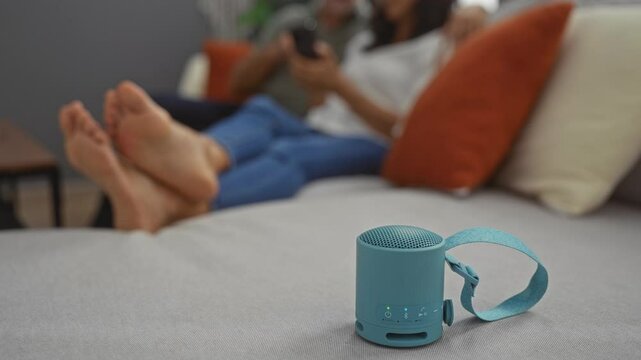 Couple relaxing in modern living room with bluetooth speaker on couch together enjoying time indoors.