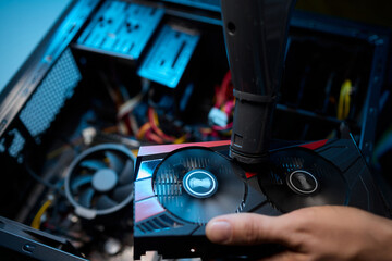 A man cleans a computer case with a vacuum in a bright room, stressing workspace tidiness