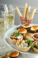 Many different tasty canapes and wine on white table, closeup