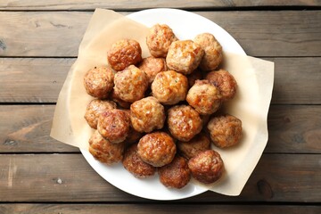 Many delicious meatballs on wooden table, top view