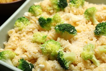 Uncooked pasta casserole with cheese and broccoli in baking dish on table, closeup