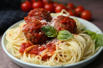 Delicious pasta with meatballs, basil and cheese on brown textured table, closeup